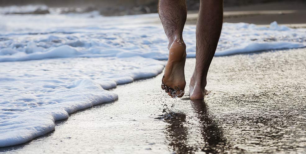 man running on beach barefoot